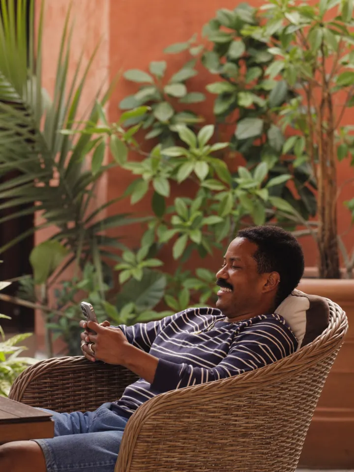 A guest relaxing in a guesthouse courtyard using a phone